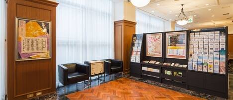 A lobby with a wooden herringbone floor, black leather chairs, a reception desk, and a wall with informational displays.
