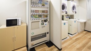 A self-service laundry area with a vending machine, microwave, and washing machines. - JR East Hotel Mets Mito (Mito)