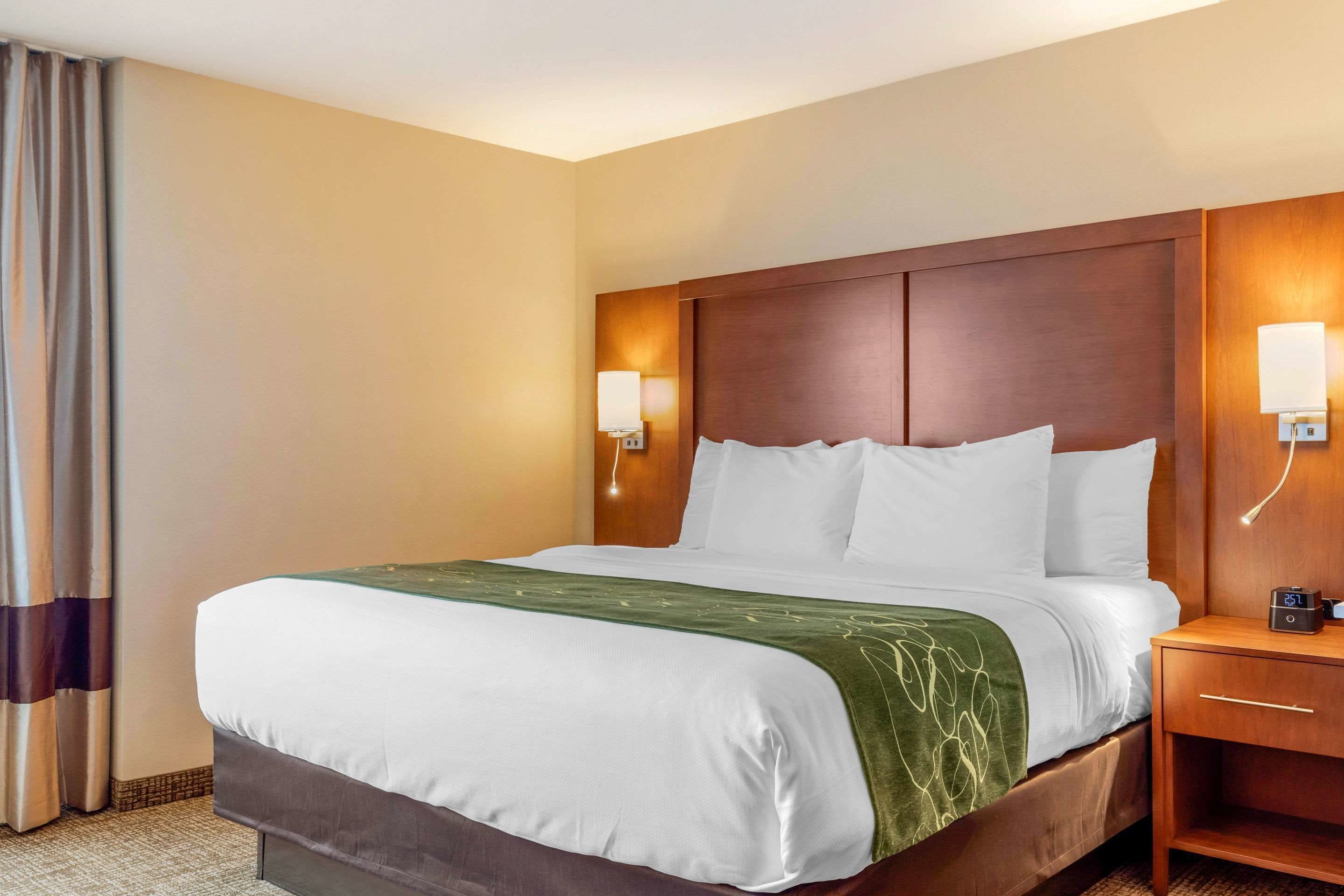 Ein Hotelzimmer mit einem großen Bett, einem Holzkopfteil, Nachttischlampen und einem Nachttisch.
