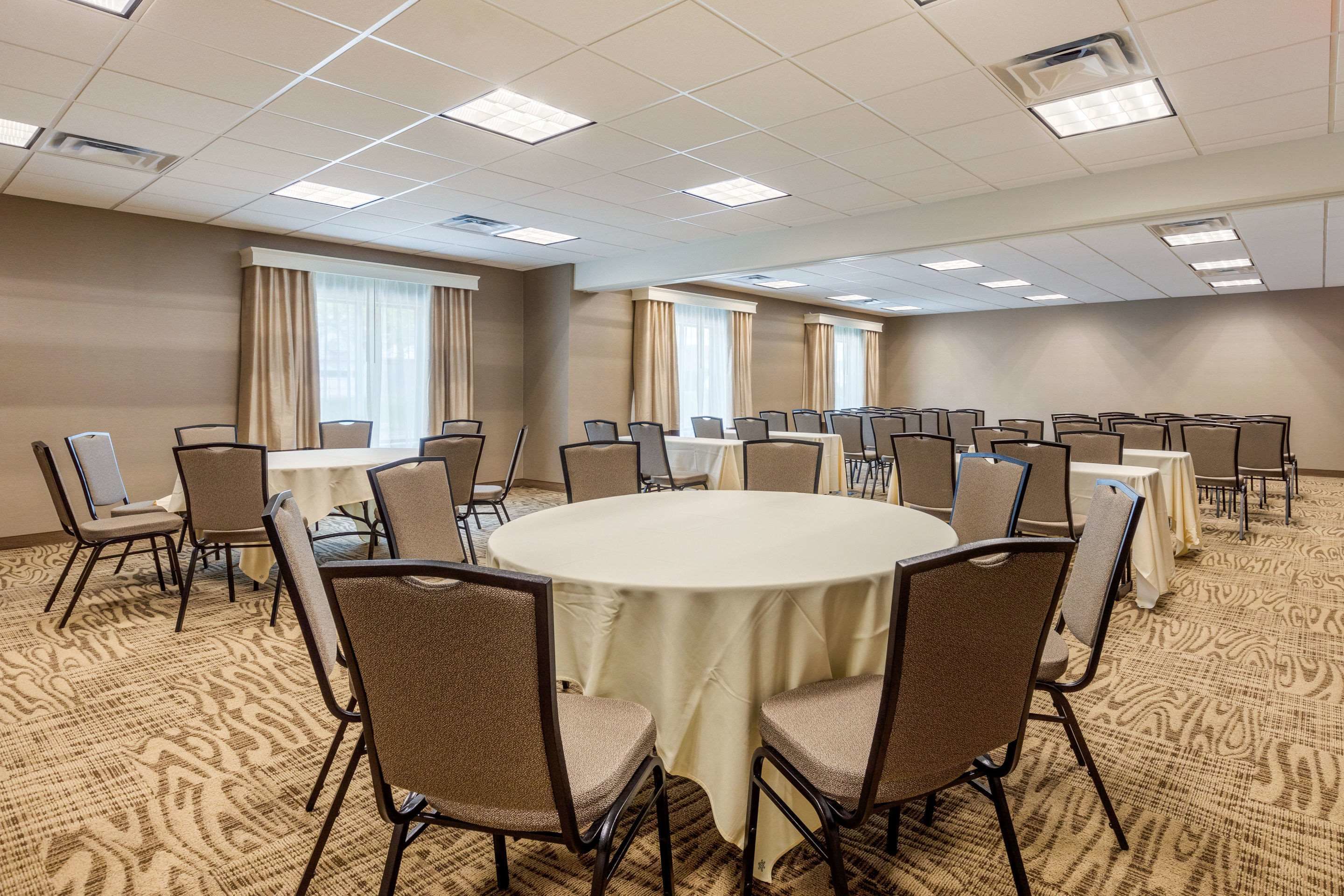 A conference room with a round table, multiple chairs, and a carpeted floor.