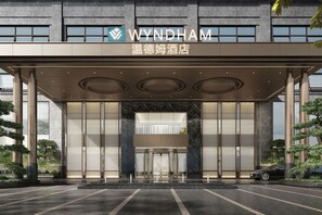 A modern hotel entrance with a large glass facade, a prominent WYNDHAM sign, and a well-maintained exterior with symmetrical columns and landscaping. - WYNDHAM WENZHOU (Wenzhou)
