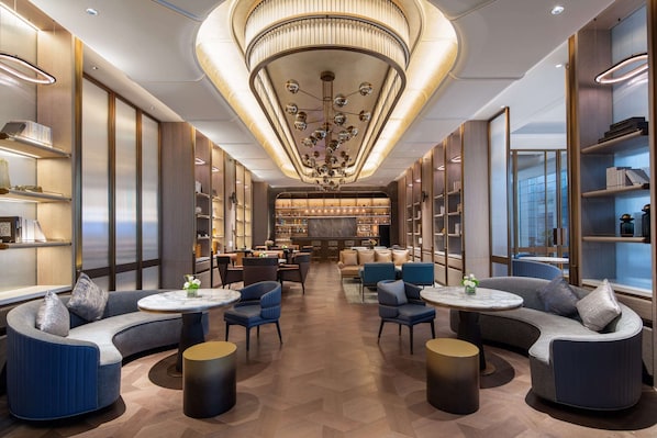 A modern lounge area with curved sofas, round tables, and a central chandelier. - WYNDHAM WENZHOU (Wenzhou)