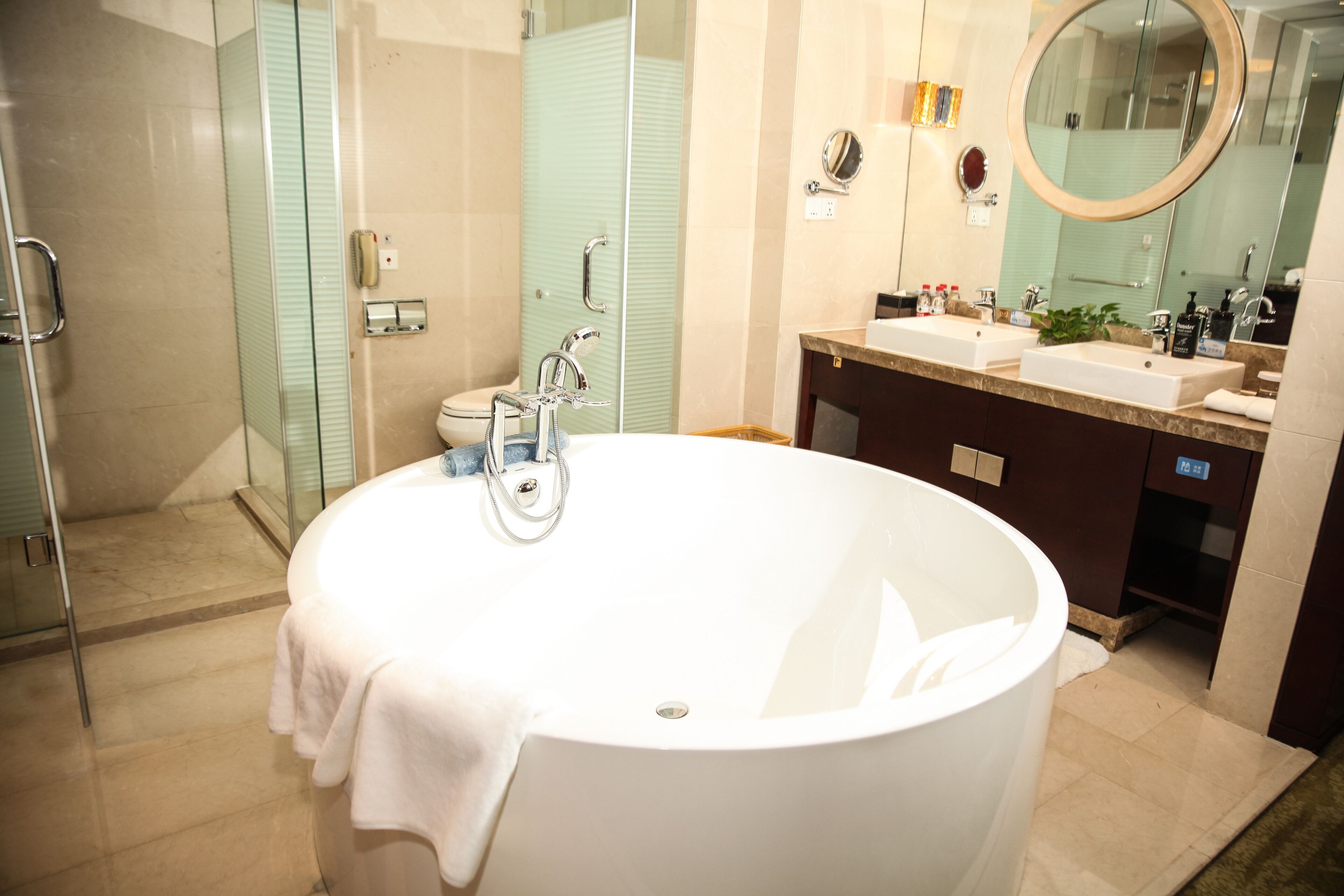 A modern bathroom with a large freestanding bathtub, a glass-enclosed shower, and a double sink vanity.