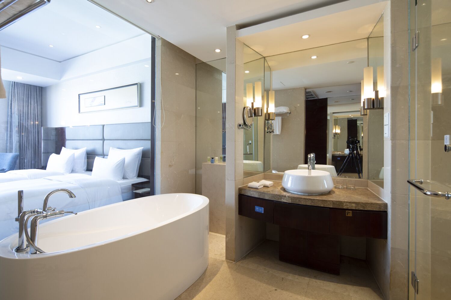 Un baño de hotel moderno con una bañera independiente grande, un tocador doble y un espejo amplio.