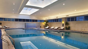 An indoor swimming pool with skylights, lounge chairs, and a tiled wall. - WYNDHAM WENZHOU (Wenzhou)