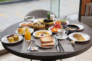 A breakfast table with various dishes including toast, eggs, fruit, and beverages. - WYNDHAM WENZHOU (Wenzhou)