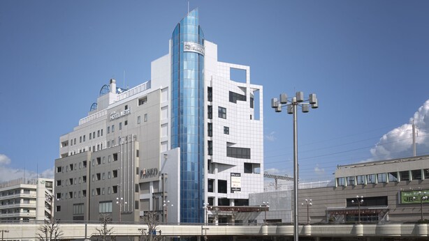 A modern hotel with a prominent glass tower and multiple floors.