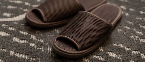 A pair of brown mesh slippers on a patterned carpet.
