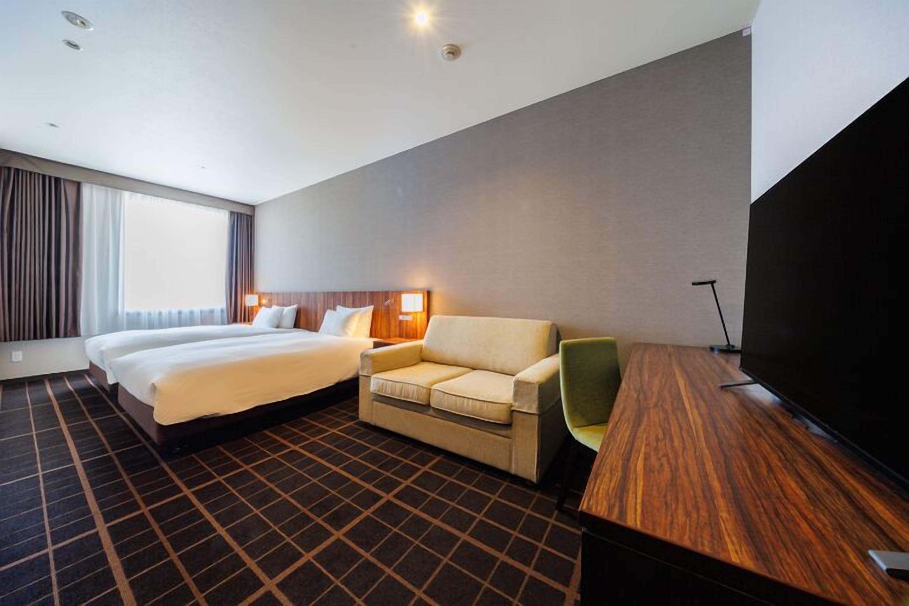 Une chambre d’hôtel avec un grand lit, un canapé, une télévision et un bureau.