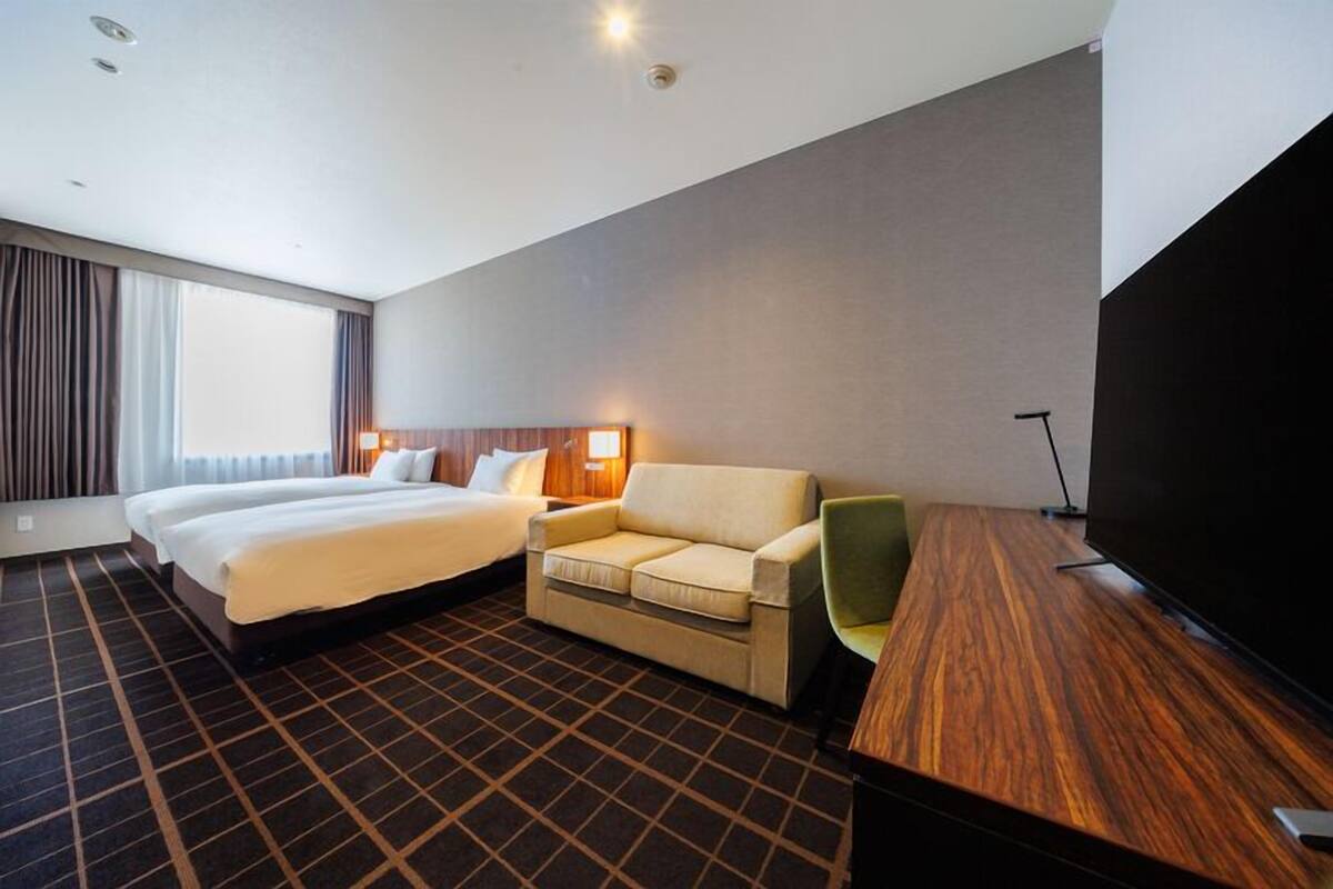 Een hotelkamer met een groot bed, een bank, een televisie en een bureau.