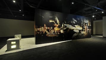 Un espacio amplio y oscuro con una estructura cúbica iluminada y una pantalla grande en la pared.