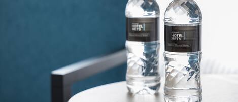 Dos botellas de agua con etiquetas sobre una mesa redonda de madera.