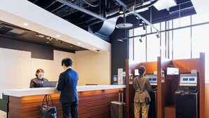 A reception area with a wooden counter, a ticketing machine, and a luggage storage box.