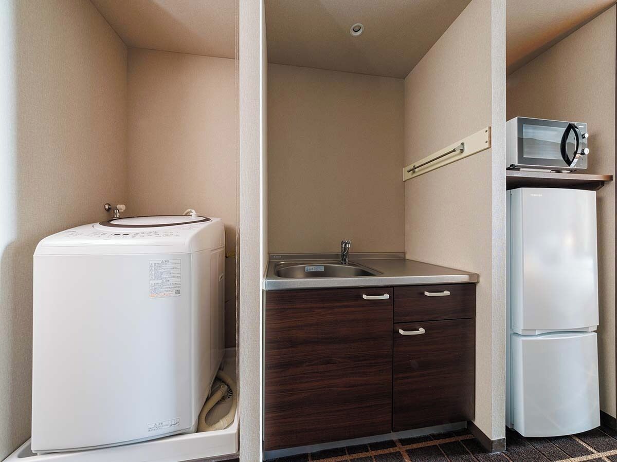 A compact kitchen with a refrigerator, microwave, sink, and cabinets.