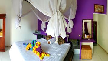 A room with a bed, a wooden door, a purple wall, and a mirror.