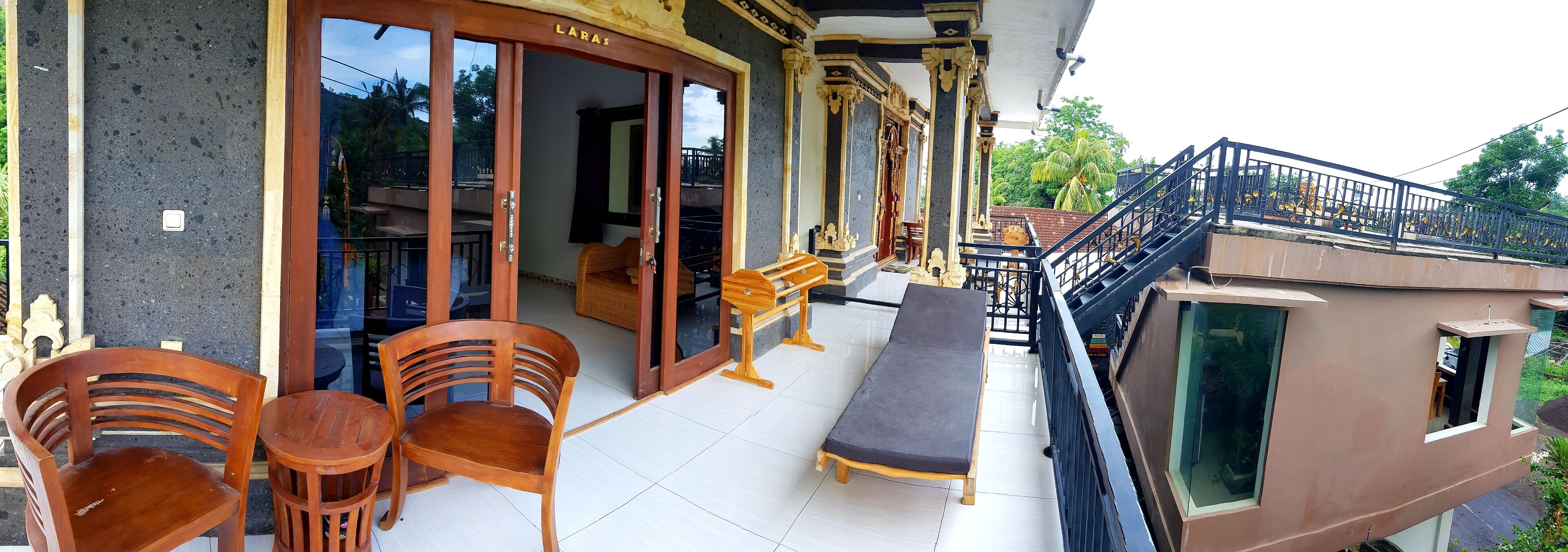 A balcony with wooden furniture, a cushioned bench, and a staircase leading to an upper level.