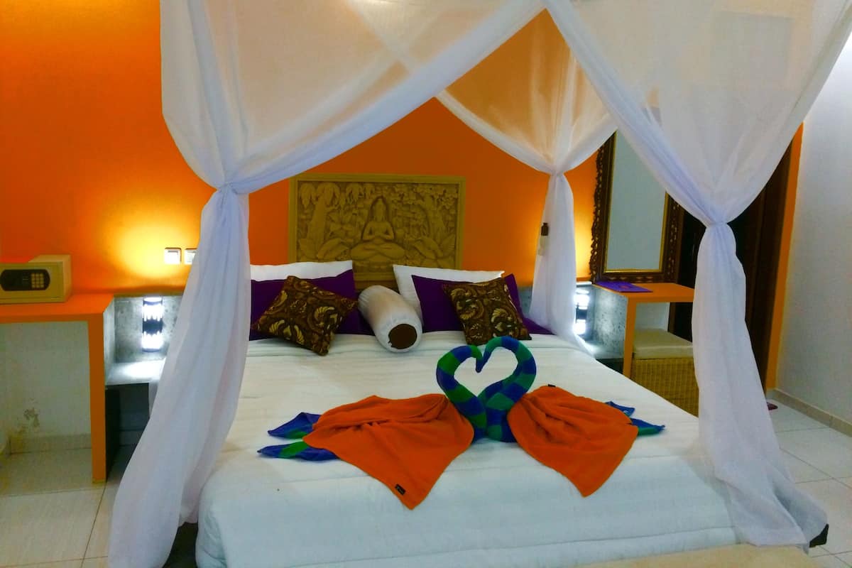 A bed with a canopy, pillows, and a decorative swan towel arrangement.