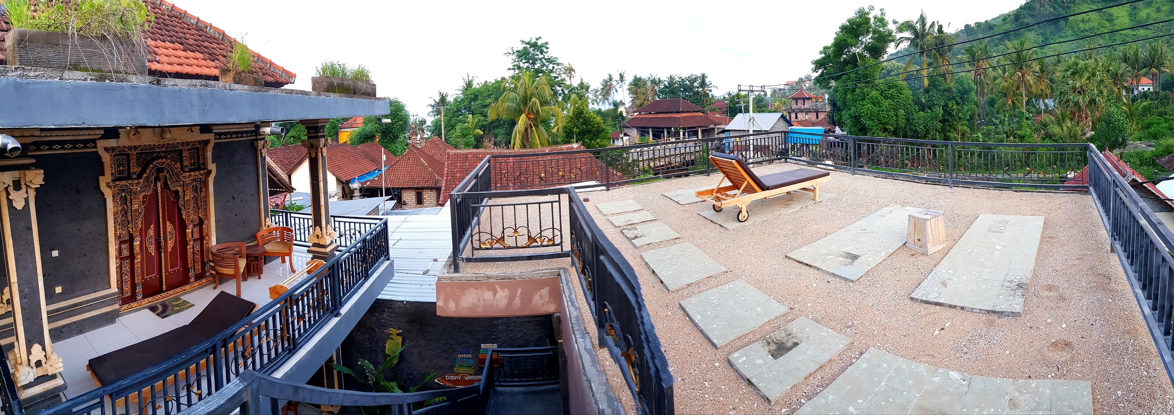 A rooftop terrace with a seating area, a staircase, and a view of surrounding buildings and greenery.