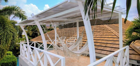 A covered outdoor area with a hammock and a white railing. - Leelawadee Pool Villa (Sattahip)