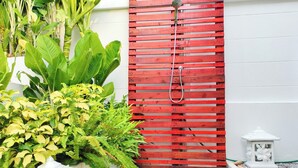 A red wooden gate with a showerhead, surrounded by lush greenery and a white wall. - Leelawadee Pool Villa (Sattahip)