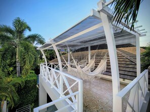A covered outdoor seating area with hammocks and a white railing. - Leelawadee Pool Villa (Sattahip)