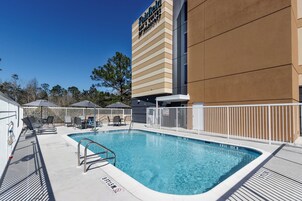 Una piscina al aire libre, sombrillas, sillones reclinables de piscina