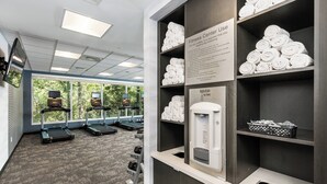 A fitness center with treadmills, a hydration station, and neatly stacked towels.
