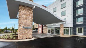 A Fairfield Inn & Suites by Marriott hotel with a modern entrance, stone pillar, and a covered walkway.