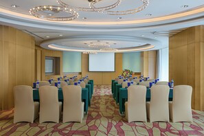 A conference room with rows of tables and chairs, a projector screen, and a floral arrangement. - Crowne Plaza Zhongshan Wing on City (Zhongshan)