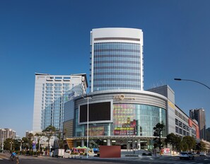 A modern building with a curved facade and large glass windows, surrounded by other high-rise buildings. - Crowne Plaza Zhongshan Wing on City (Zhongshan)