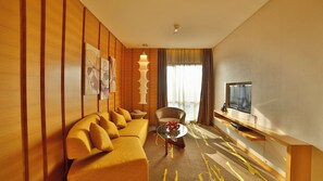 A hotel room with a sofa, a glass coffee table, a TV, and a decorative lamp. - Crowne Plaza Zhongshan Wing on City (Zhongshan)