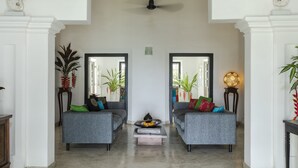 A spacious living area with two grey sofas, a coffee table with books and fruit, and decorative plants. - Coco Tangalla (Tangalle)