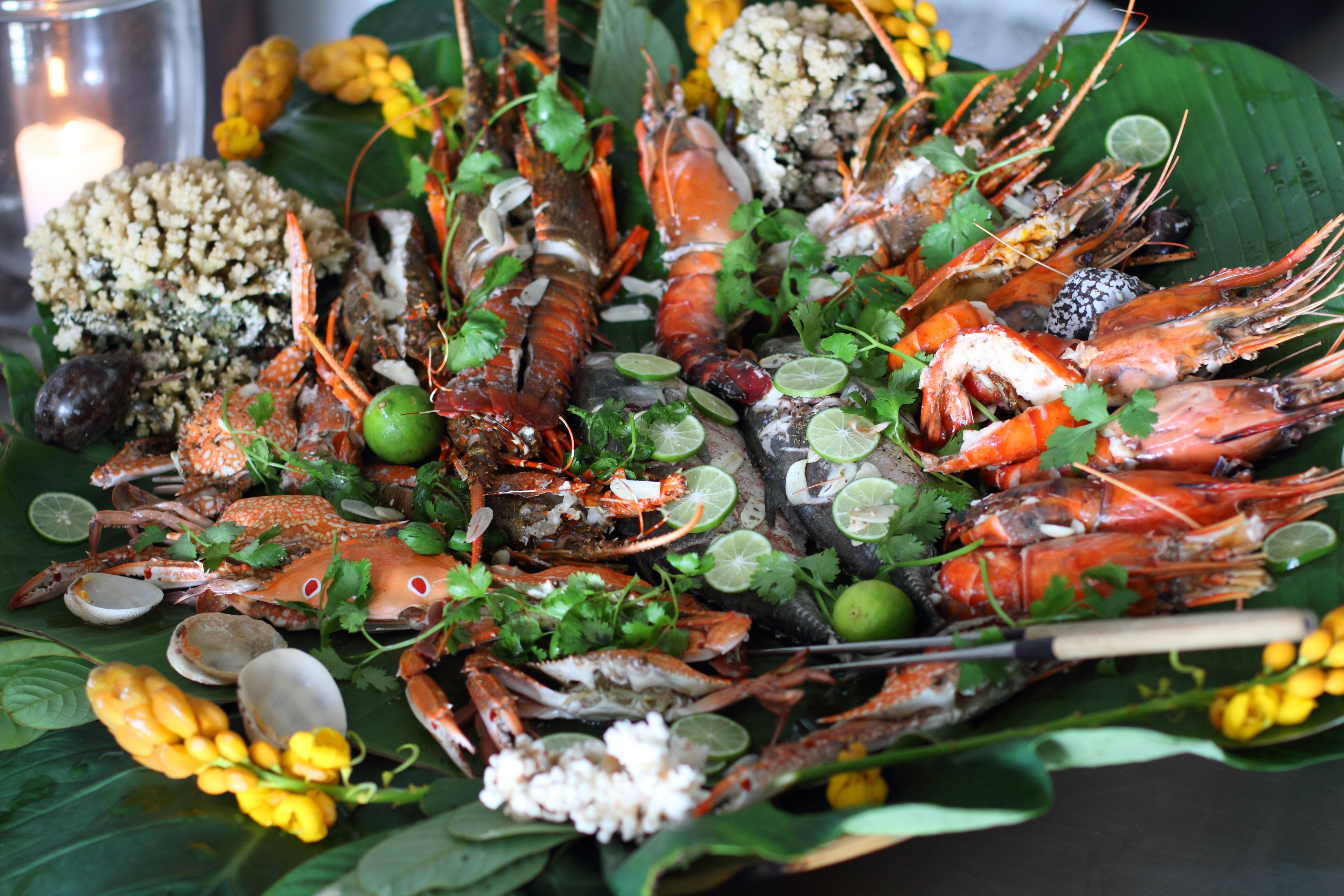 A seafood platter with various types of shellfish, garnished with herbs and lime.