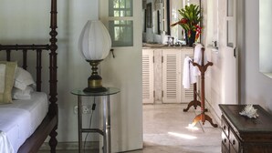 A bedroom with a four-poster bed, a bedside table with a lamp, and a dresser. - Coco Tangalla (Tangalle)