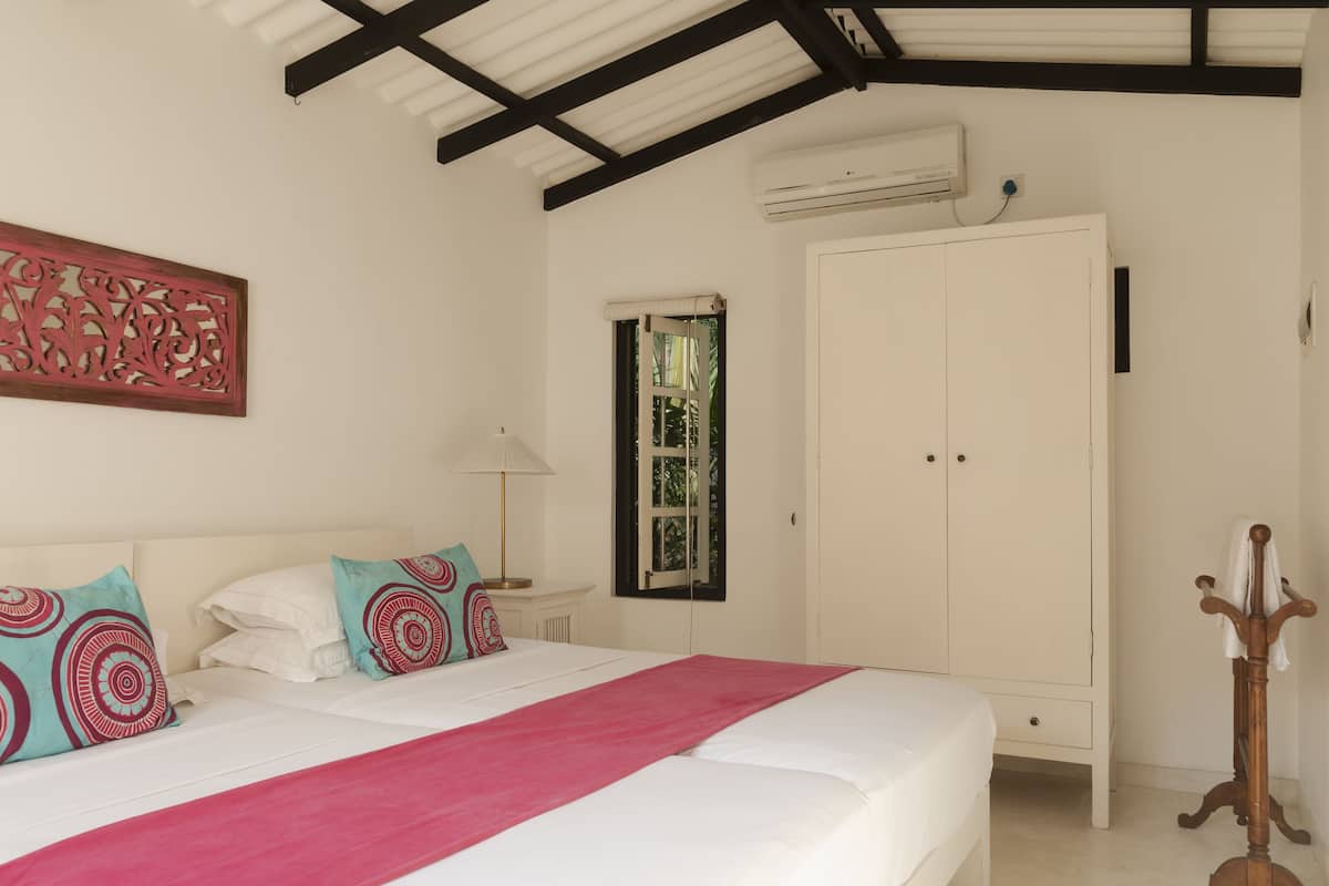 Quarto com cama, guarda-roupa, janela e um objeto decorativo na parede.