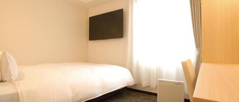 Quarto de hotel com cama, televisão de tela plana na parede, janela com cortinas e radiador.