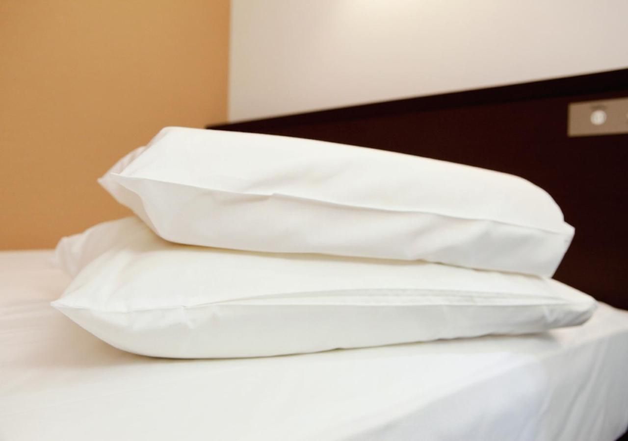 Ein ordentlich bezogenes Bett mit weißer Bettwäsche und Kissen.