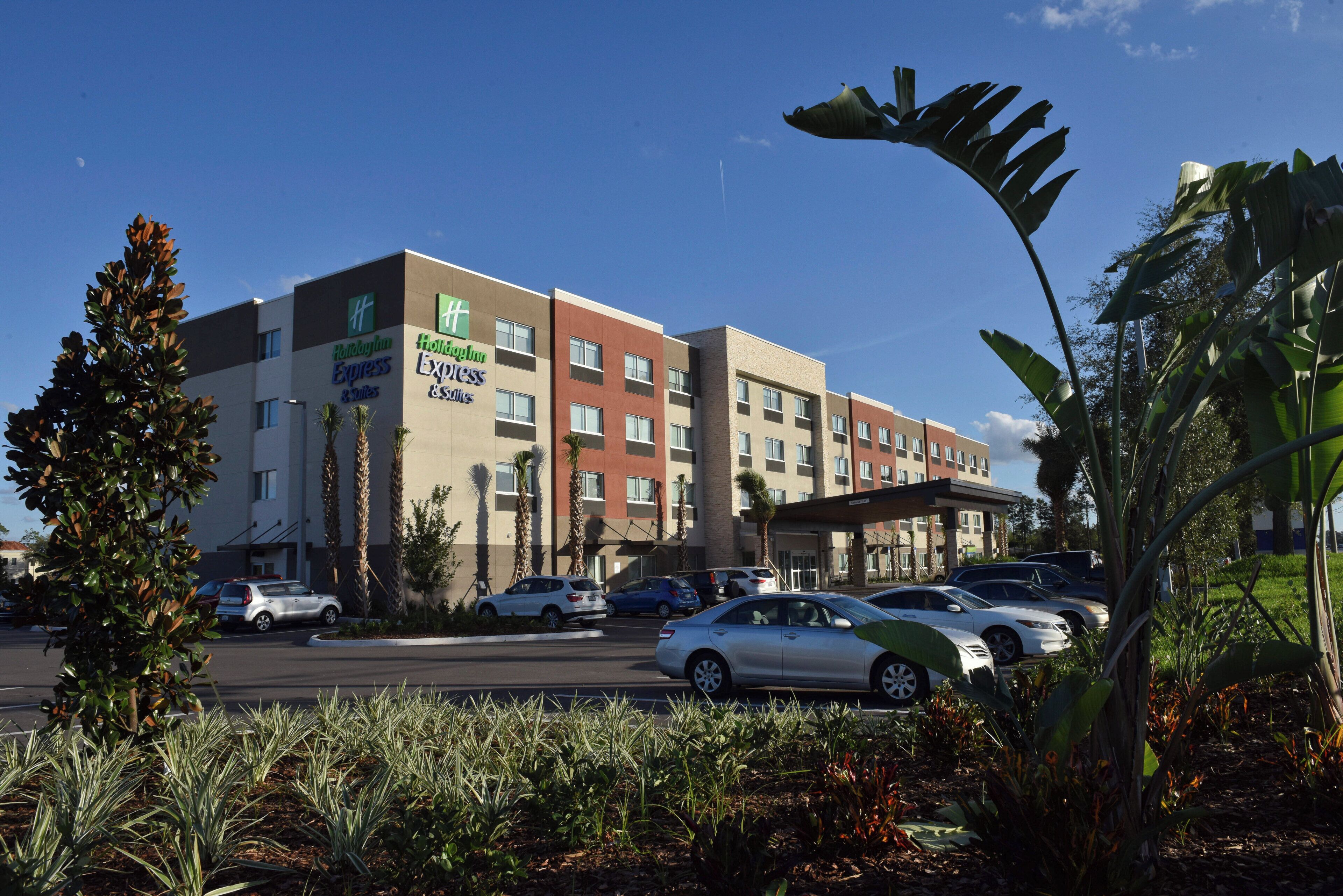 A Holiday Inn Express building with multiple floors, a parking lot, and surrounding greenery.