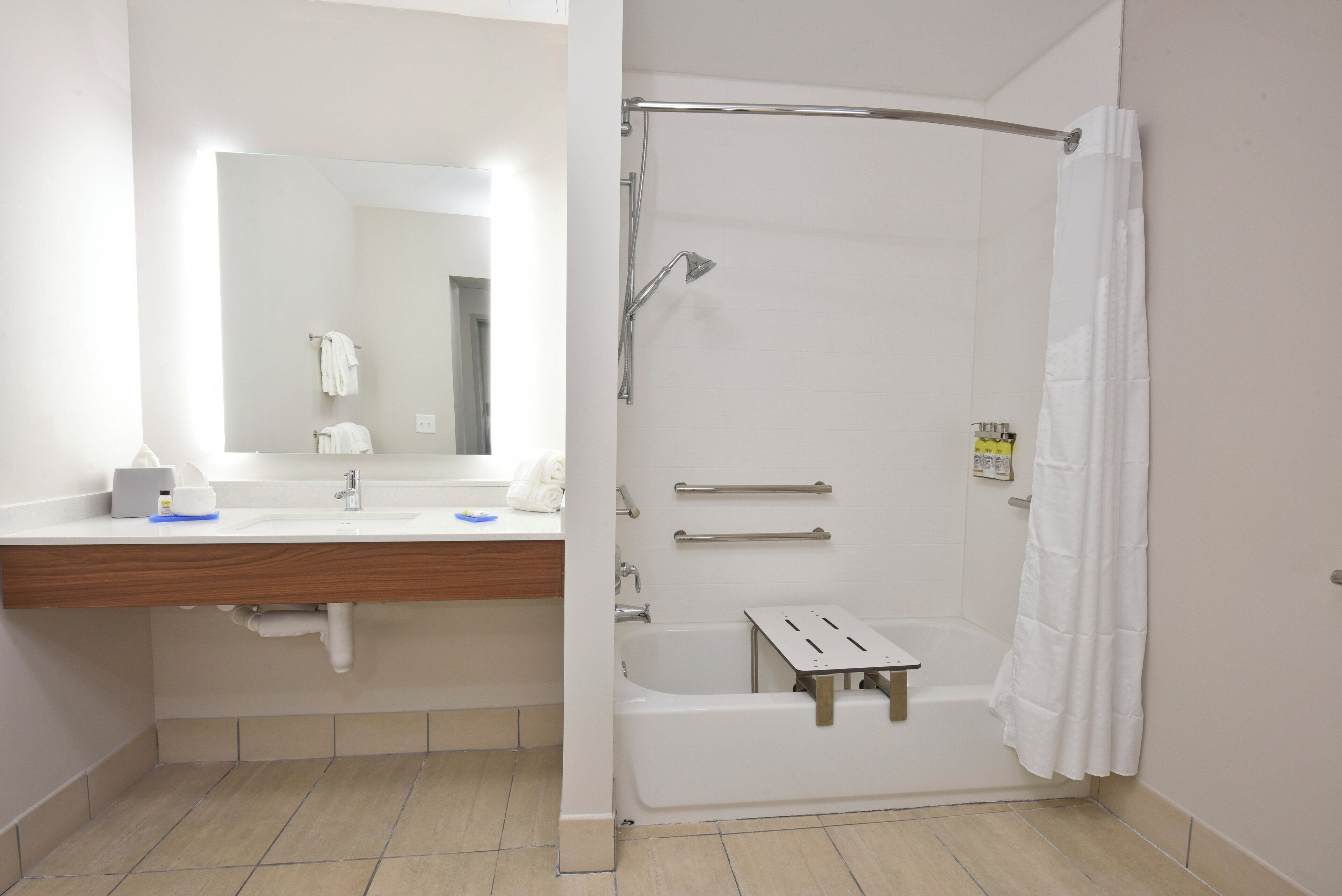 A bathroom with a shower, a sink, and a mirror.
