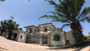 A two-story house with a gated entrance, a covered patio, and a large palm tree in the foreground. - Baan TonPalm Pool Villa Huahin (Hua Hin)
