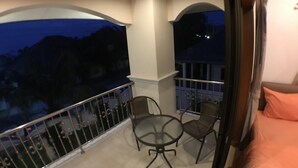 A balcony with a glass table and two chairs, overlooking a dark landscape. - Baan TonPalm Pool Villa Huahin (Hua Hin)
