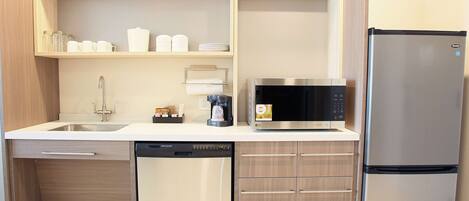 A compact kitchen with a dishwasher, microwave, and refrigerator.