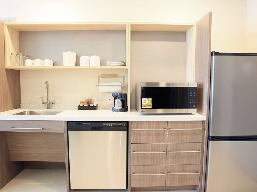 A compact kitchen with a dishwasher, microwave, and refrigerator.
