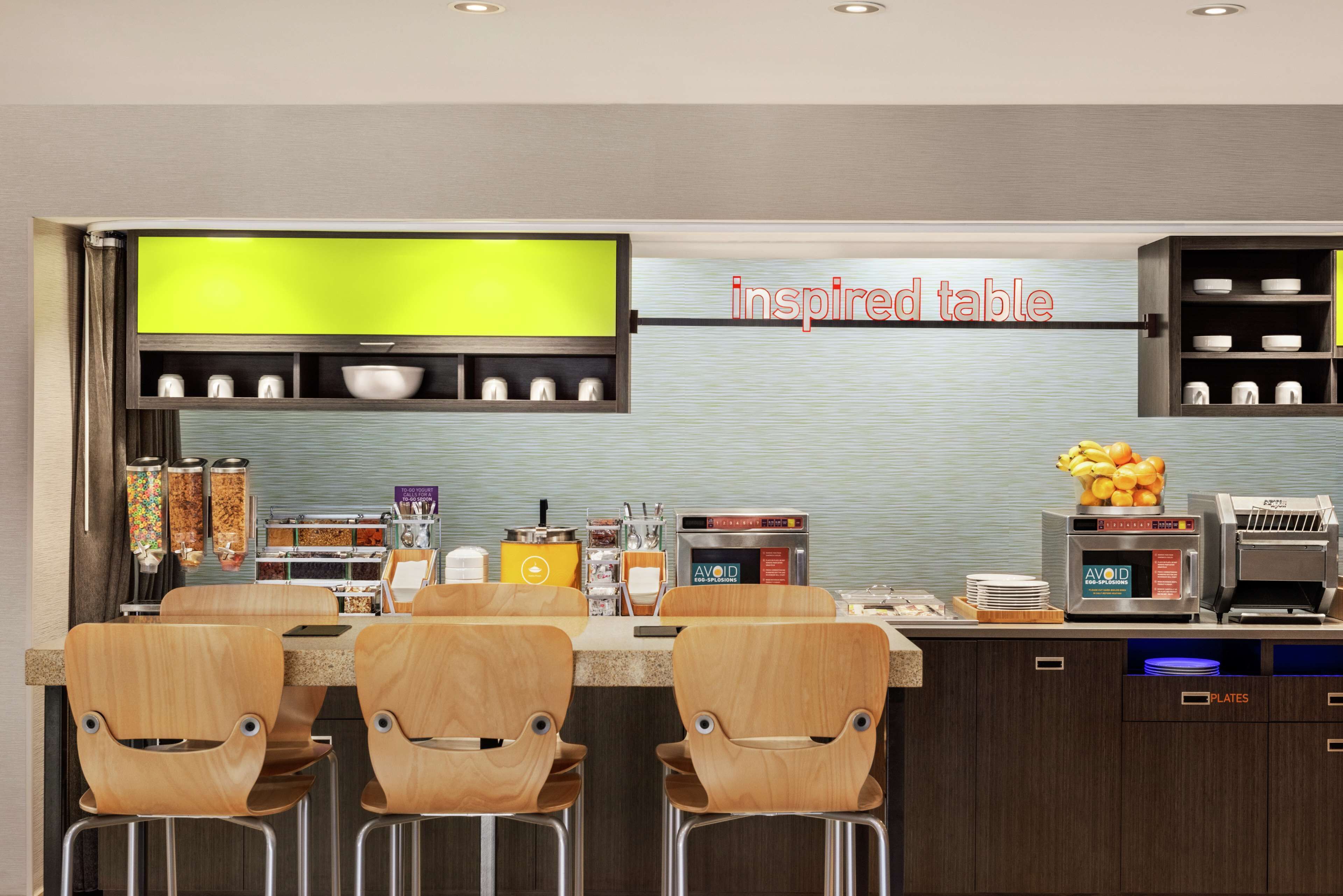 A modern kitchen with a bar area, equipped with a coffee machine, microwave, and various utensils.
