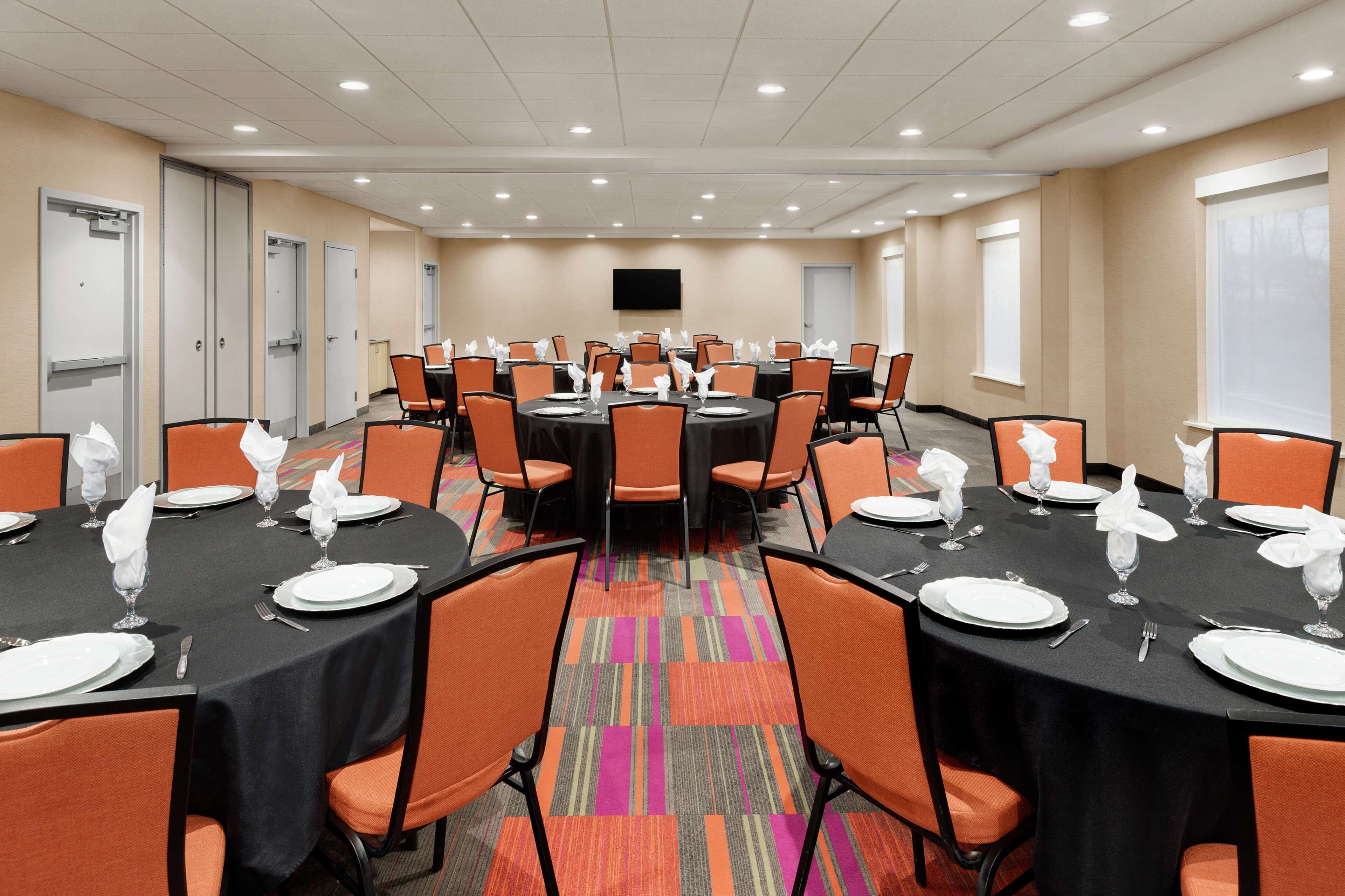 A conference room with multiple tables set for dining, equipped with chairs and tables.