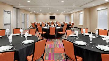 A conference room with multiple tables set for dining, equipped with chairs and tables.