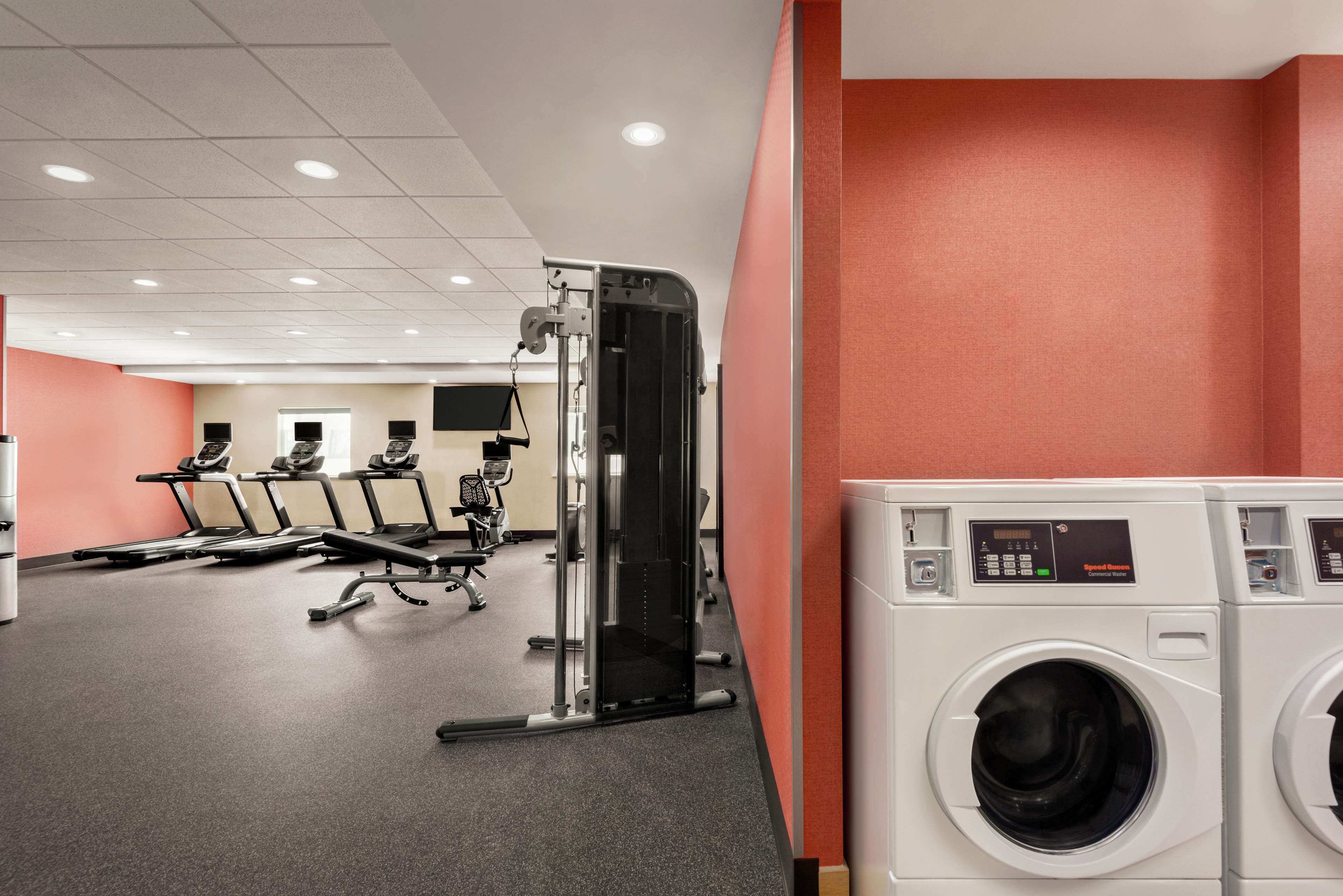 A fitness center with exercise equipment, a treadmill, and a washing machine.