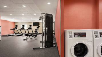 A fitness center with exercise equipment, a treadmill, and a washing machine.