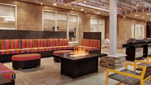 An outdoor seating area with colorful striped sofas and a fire feature. - Home2 Suites by Hilton Woodbridge Potomac Mills (Woodbridge)