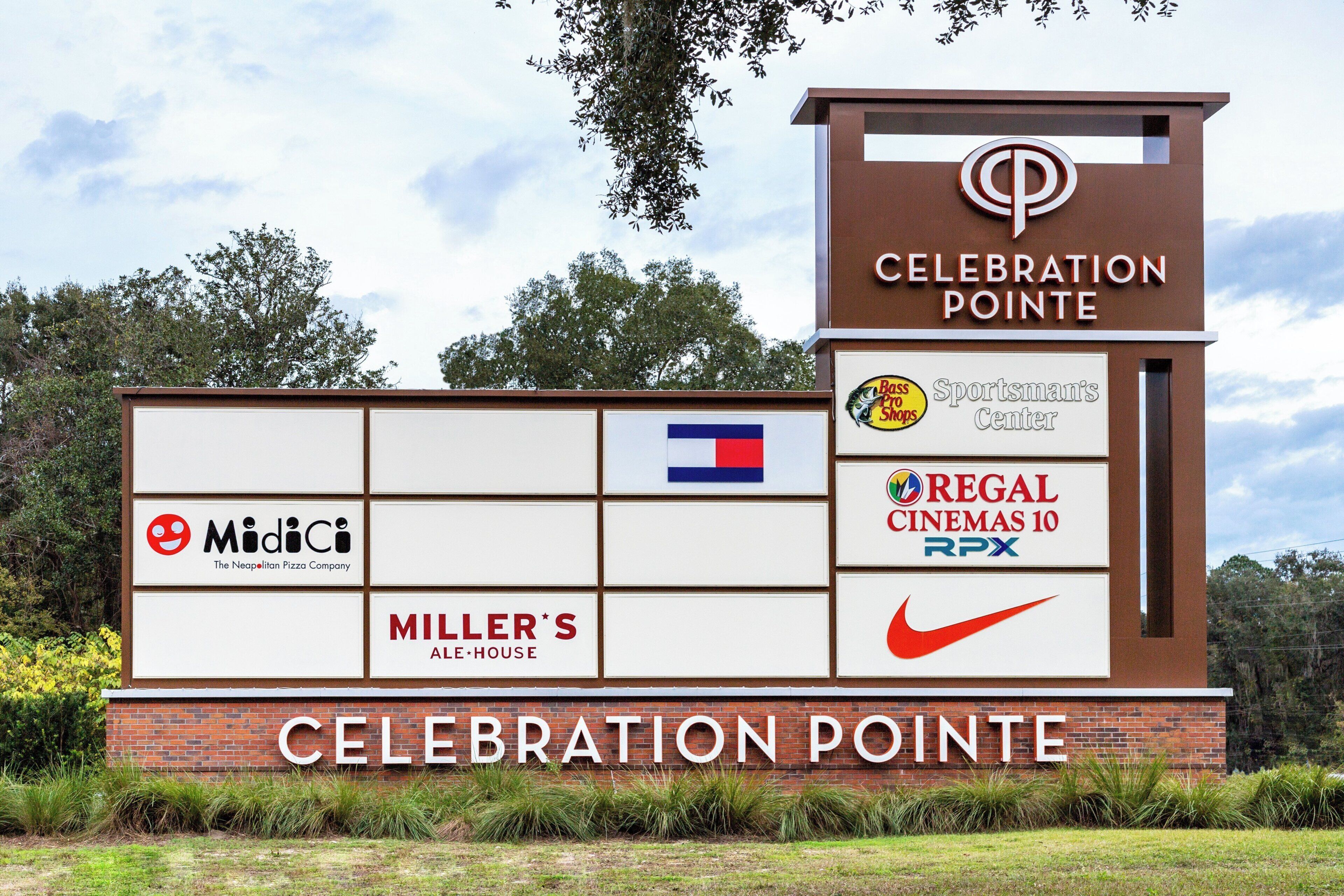 A signboard with the text 'CELEBRATION POINTE' and logos of various businesses including 'MidlCi', 'MILLER'S', 'REGAL CINEMAS 10', and 'Sportsman's Center'.